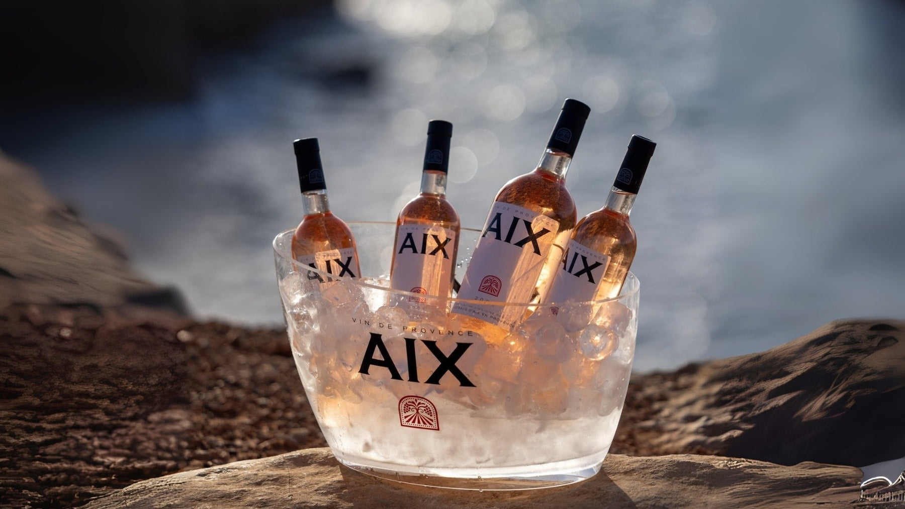 Maison Saint AIX rosé bottles in large and small formats displayed in an ice budcket by the sea.
