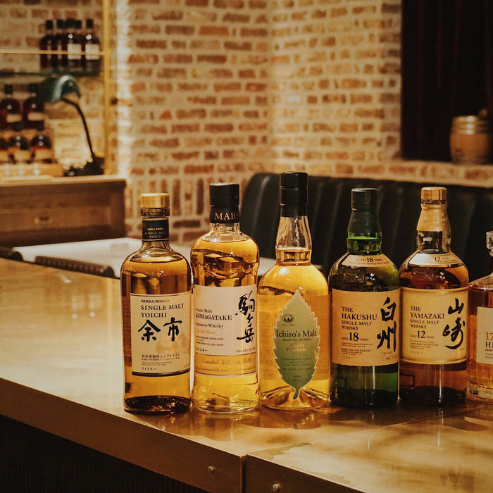 Assorted Japanese whisky bottles displayed on a bar, including Yamazaki, Hakushu and Hibiki